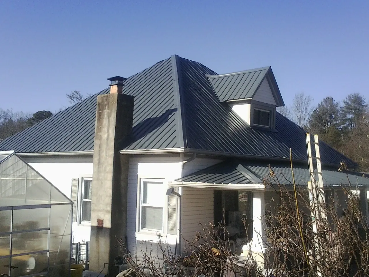 Dark blue standing seam metal roof on a white farmhouse with dormer — Slate & Tile Roof Repair by Roofing Brothers in Cold Spring