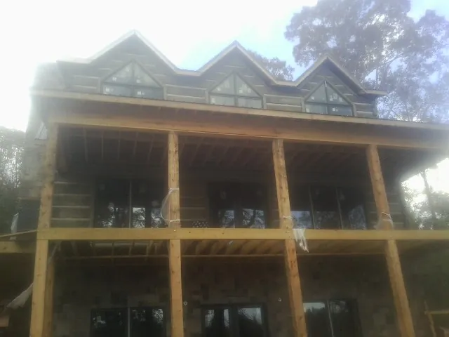 Dormers and porch framing on a large log home under construction — Roof Coating work by our crew in Cold Spring